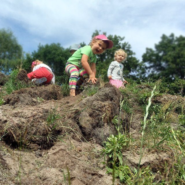 Kleinkinder erklimmen einen Matschberg