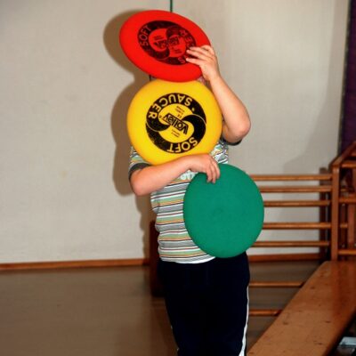 Kind mit Softfrisbees in Ampelfarbe