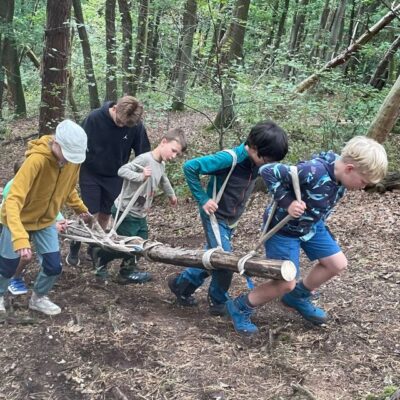 Kinder, die einen Baumstamm tragen