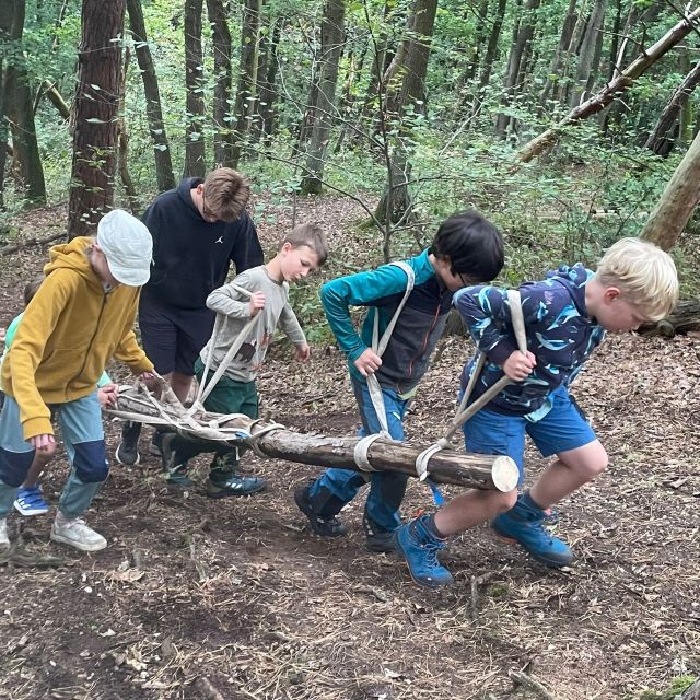 Kinder, die einen Baumstamm tragen