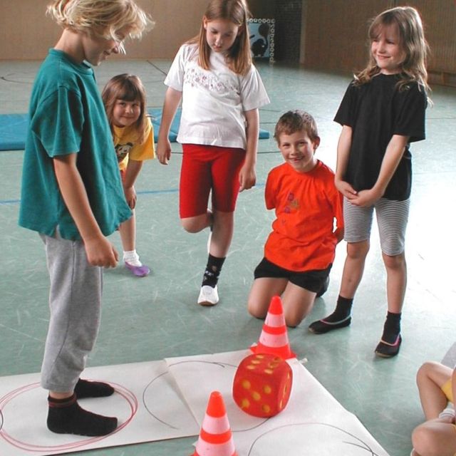 Kinder spielen mit Würfel und Kegel